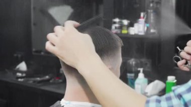 Profesyonel berber erkek müşterisinin saçını ıslatıyor ve tarıyor.