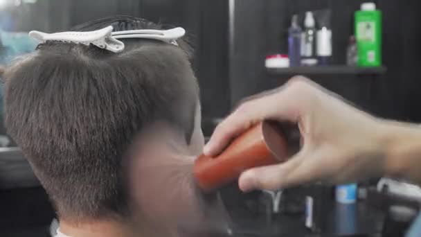 Перукар чистить волосся клієнта після стрижки. — стокове відео