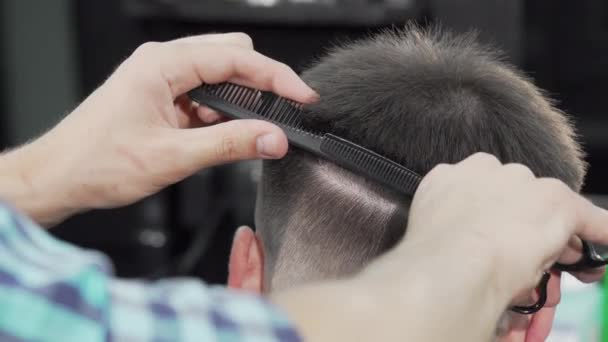 Cortado tiro de un peluquero profesional cortar el pelo de un hombre — Vídeo de stock