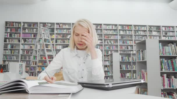 Güzel kız öğrenci kütüphanede çalışırken stres yapıyor. — Stok video