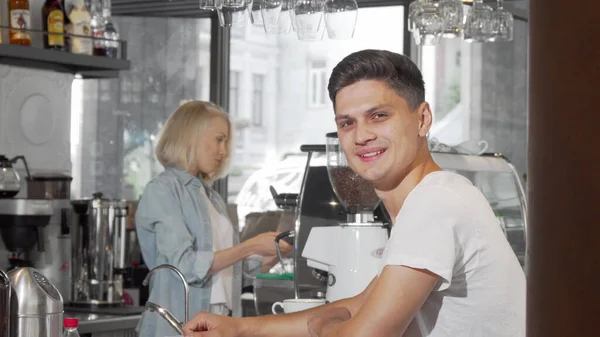 Schöner junger Mann lächelt in die Kamera, während er seinen Kaffee im Café genießt — Stockfoto