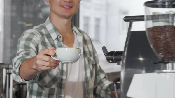 カメラに美味しいコーヒーのカップを持って微笑む幸せな男性バリスタ — ストック写真