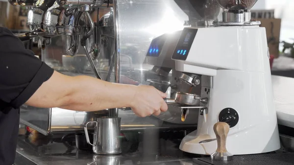 Обрезанный снимок баристы, шлифующей кофейные зерна с помощью кофеварки — стоковое фото