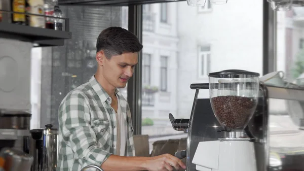 Yakışıklı neşeli erkek barista onun kafede müşteriler için kahve hazırlanıyor — Stok fotoğraf