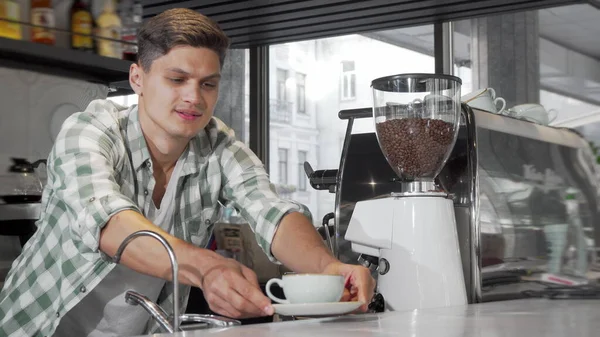 Yakışıklı erkek barista lezzetli kahve hizmet ettikten sonra kameraya gülümseyen — Stok fotoğraf