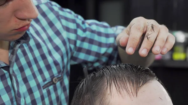 Tiro cortado de um cabeleireiro pentear o cabelo molhado de um cliente — Fotografia de Stock