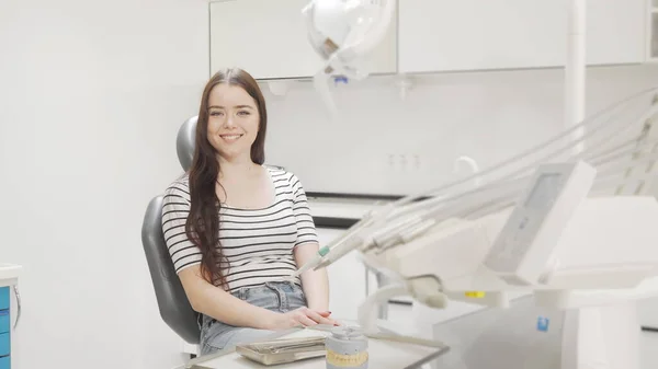 Lovely young woman getting into dental chair smiling to the camera — Stock Photo, Image