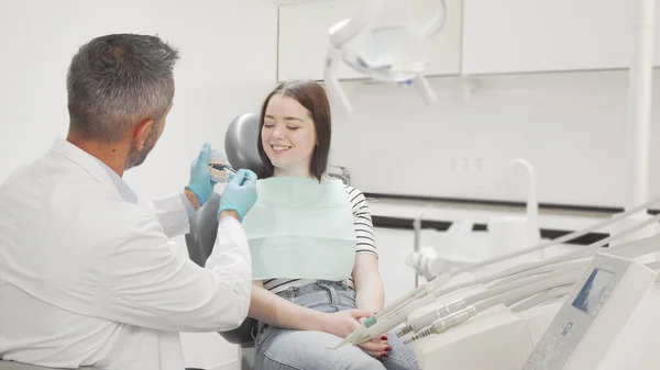 Adorável jovem aprendendo sobre cuidados dentários de seu dentista — Fotografia de Stock