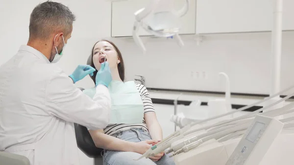 Jovem paciente do sexo feminino obtendo seus dentes examinados pelo dentista — Fotografia de Stock