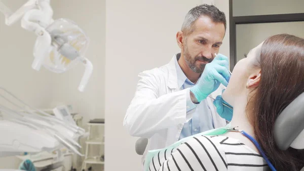 Mature male dentist examining teeth of a female patient — Stock Photo, Image