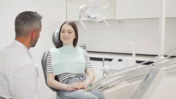 Una joven encantadora hablando con su dentista en la clínica — Foto de Stock