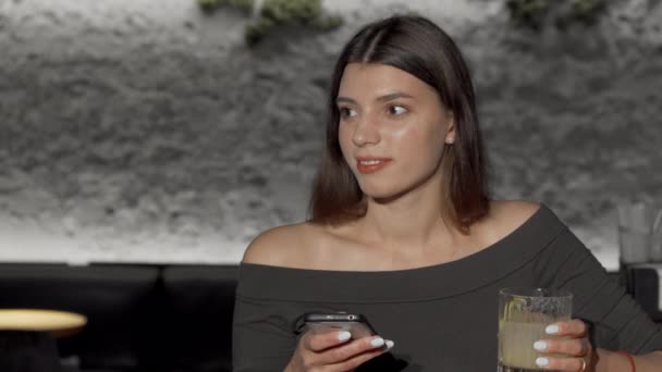 Härlig ung kvinna som använder smart telefon medan du dricker i baren — Stockvideo
