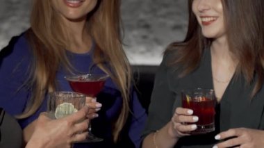 Barda kokteyl bardaklarını tokuştururken çekilmiş üç kız arkadaş fotoğrafı.
