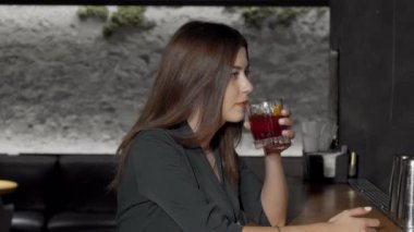 Kokteyl içerken kameraya gülümseyen hoş bir genç kadın.