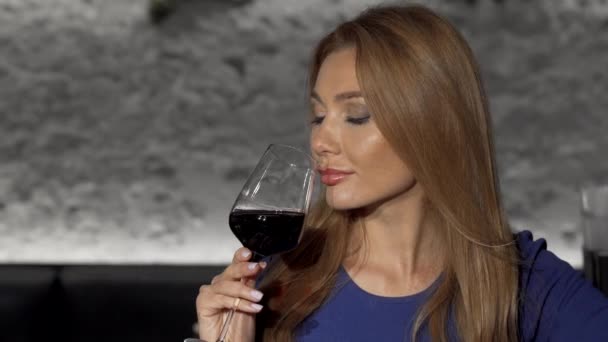 Schöne entspannte Frau trinkt Rotwein