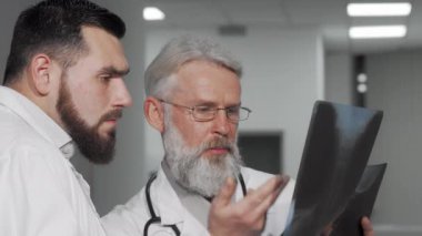 Kıdemli erkek doktor ve meslektaşı bir hastanın röntgen taramasını tartışıyorlar.