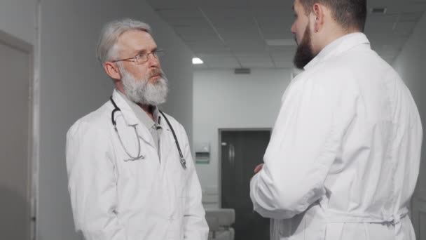 Старший лікар потискає руки зі своїм колегою в лікарні — стокове відео