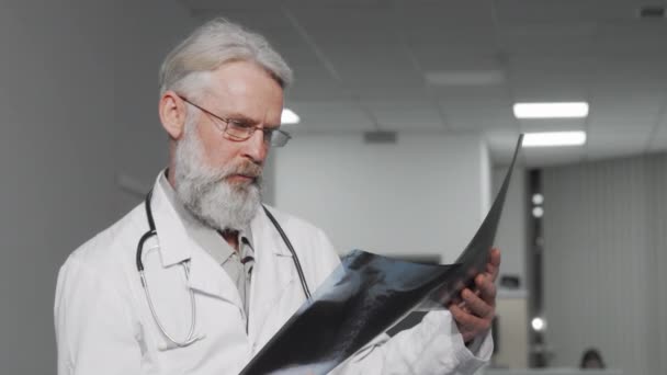 Врач-пожилой мужчина осматривает рентген пациента — стоковое видео