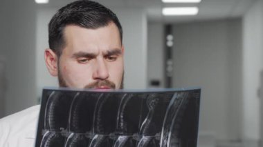 MRI taramasından sonra kameraya gülümseyen sakallı erkek doktor.