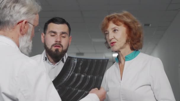 Läkarteam diskuterar MRT-skanningar av en patient tillsammans — Stockvideo