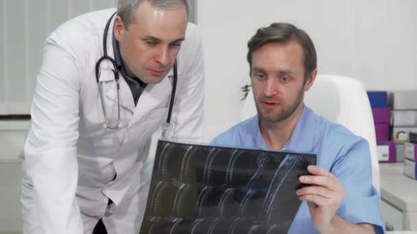 Ώριμος άνδρας χειρουργός ζητά τη συμβουλή του συναδέλφου του για τη μαγνητική τομογραφία του ασθενούς — Αρχείο Βίντεο