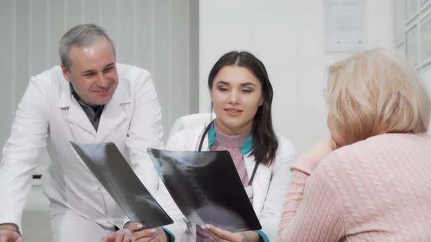 Twee artsen die röntgenscans van oudere vrouwen onderzoeken — Stockvideo