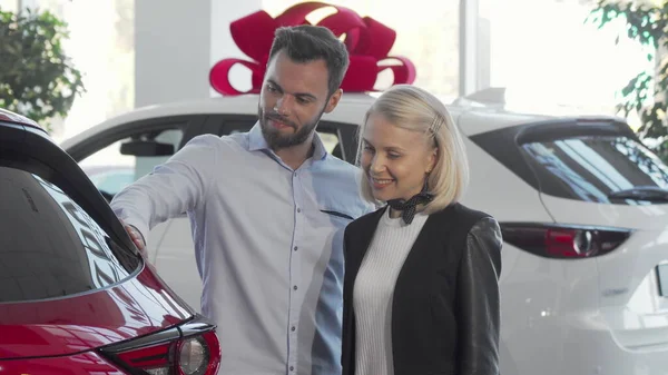 Молодая пара выбирает автомобиль для покупки в автосалоне — стоковое фото
