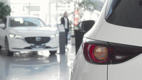 Female customer choosing automobile to buy at dealership salon