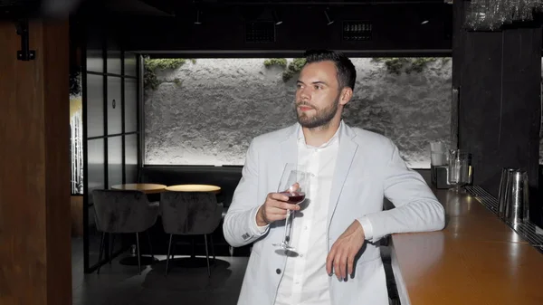 Guapo joven elegante disfrutando de beber vino en el bar —  Fotos de Stock