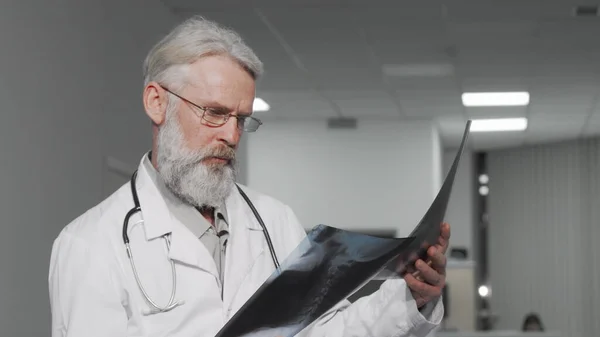 Врач-пожилой мужчина осматривает рентген пациента — стоковое фото