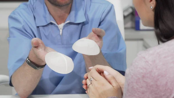 Ahli bedah plastik menunjukkan dua implan payudara untuk pasien perempuan — Stok Foto