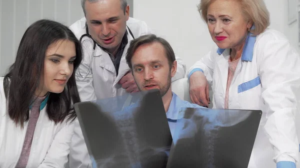 Grupo de médicos discutindo exames de raios-x de um paciente juntos — Fotografia de Stock