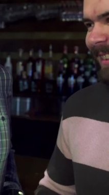 Üç neşeli Kafkasyalı arkadaş coşkulu bir barda neşe içinde bira bardaklarını tokuşturarak yoldaşlık ve heyecan saçıyorlar. Yakın çekim onların hareketli gülümsemelerini ve canlı atmosferini yakalar, kahkahalarla ve bar ışıklarının sıcacık parıltılarıyla