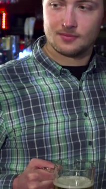 Üç neşeli Kafkasyalı arkadaş canlı bir barda kadehlerini kaldırarak arkadaşlığı canlandırılmış ifadelerle kutluyorlar. Yakın plan çekimler, ışıldayan bira fincanlarını birbirine vurarak neşeli ve neşeli bir atmosferde neşe ve dostluk saçarak yakalar.