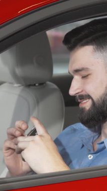 Şık sakallı neşeli bir adam, sürücü koltuğundan gözleri kamaştıran kırmızı arabasının anahtarlarını tutarken gururla ışıldıyor. Bu canlı an, yeni sahipliğin heyecanını ve yeni maceralara atılmanın heyecanını özetliyor.