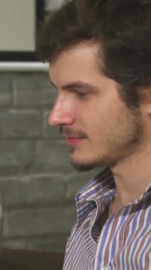 Yakın plan çekimde kendine güvenen genç bir iş kadını, erkek arkadaşıyla şık, modern bir ofiste ateşli bir tartışmaya girerken ışıl ışıl gülümseyen bir gülüşü görülüyor. Enerjik etkileşimleri yaratıcılık ve pozitiflik yayar.