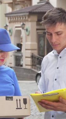 Zarif beyaz gömlekli şık bir genç adam, dost canlısı bir bayan kuryenin elinde tuttuğu bir paket için olumlu enerji yayıyor. Büyüleyici kentsel ortam, modern dağıtım hizmetlerinin düzgün etkileşimini ve verimliliğini vurgulayarak sahneyi geliştiriyor.