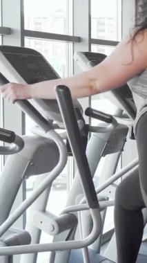 Parlak, modern bir spor salonunda şık eliptik spor ayakkabıları üzerinde egzersiz yaparken kendine güvenen iki iri kadın, canlı bir sohbete girişiyor. Hareketli spor kıyafetleri ve bulaşıcı enerjileri arkadaşlıkla dolu ilham verici bir atmosfer yaratıyor.