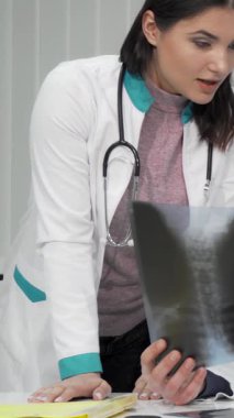 Gösterişli, iyi aydınlatılmış bir klinikte, kendini adamış bir erkek doktor ve özenli bayan meslektaşı yaşlı bir hastanın röntgen taramalarını yakından inceliyor. Bağlı oldukları bu konuşma, sağlık hizmetlerinde işbirliğinin hayati rolünü yansıtıyor ve merhameti vurguluyor.