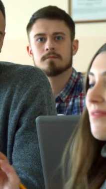 Canlı bir kolej konferans salonunda, hayat dolu bir kız öğrenci erkek sınıf arkadaşıyla neşeli bir kahkaha paylaşıyor, arkadaşlıkla dolu çekici bir atmosfer yaratıyor. Çekici beyaz kız, dalgalı uzun saçlı, notlarına dalmış,