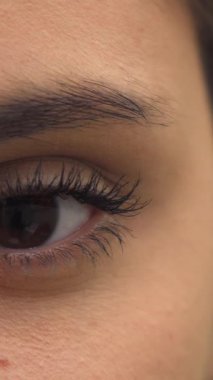 Genç esmer bir kadının büyüleyici yakın çekimi gözlerini nazikçe açarken uzun, tatlı kirpikleri ve ışıl ışıl bir gülümsemesi ortaya çıkıyor. Göz kapağının karmaşık ayrıntıları ve gözlerindeki ışıltı güzellik ve özgüven yayıyor.