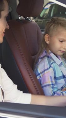 Renkli bir ekose gömlek giymiş keyifli küçük bir kız, yeni lüks bir arabanın direksiyonunu sıkıca kavrıyor, babası yanında gururla parıldıyor. Zengin kahverengi deri ve modern teknolojiyle süslenmiş gösterişli iç mekan...