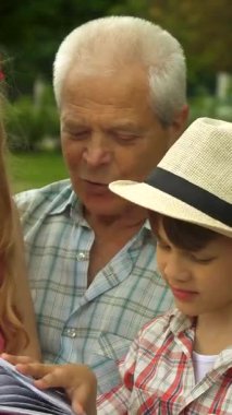 Güneşli bir parkta, büyüleyici bir büyükbaba büyüleyici torunlarıyla büyülü bir anı paylaşıyor, canlı bir hikaye kitabına dalmış. Yakışıklı son sınıf öğrencisi, gümüş saçlı, yemyeşil bir bankta otururken, güzel kızı...