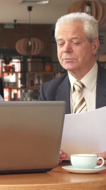 Şık bir kafede, özel dikim koyu takım elbiseli seçkin kıdemli bir işadamı ve zarif çizgili kravat önemli belgeleri incelerken, odaklanmış genç sakallı bir adam parlak dizüstü bilgisayarında özenle yazı yazıyor. Davetkar atmosfer, dumanı tüten bir atmosfer.