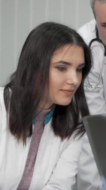 Kendini işine adamış bir grup doktor, hem erkek hem de kadın, yoğun bir şekilde röntgen taramalarını inceleyerek, hastanın bakımına olan bağlılıklarını yansıtıyor. Çağdaş tıbbi ortam işbirliği ile uğulduyor, çıtır çıtır giyinirken içgörülerini paylaşıyorlar.