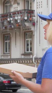 Parlak mavi üniformalı kendini işine adamış bir teslimatçı elinde pizza kutusuyla bir sonraki teslimatı için caddeyi tarıyor. Bu canlı şehir manzarası fast food servisinin heyecanını yansıtıyor.