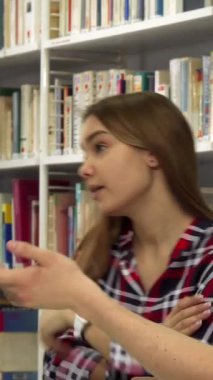 Renkli kitaplarla dolu canlı bir kütüphanede, yakışıklı sakallı bir adam dizüstü bilgisayarında kafası karışmış ama nişanlı görünen güzel kahverengi saçlı bir kızla tutkuyla bir konuyu tartışırken hareketler yapıyor. Şiddetli değişimleri...