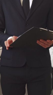 Çarpıcı bir yakın plan çekimde iki adam canlı bir araba galerisinde güven ve profesyonellik yayarak el sıkışırken görülüyor. Özel dikim siyah takım elbise giyen satış müdürü, müşterisiyle parlak gri bir elbisenin yanında etkileşime girer.