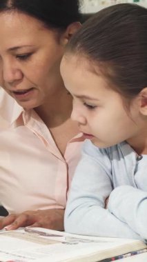 Asyalı bir anne ve sevimli küçük kızı renkli kitaplıklarla dolu, hoş bir kitapçıda hoş bir kitap okuma seansına daldılar. Bu dokunaklı sahne ailenin sıcaklığını güzel bir şekilde gösteriyor.