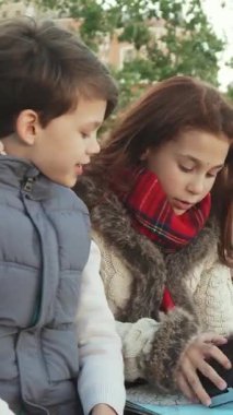 Şehrin göbeğindeki güneşli bir bankta uzun siyah saçlı bir kız ve kameradan büyülenmiş bir erkek çocuğu. Rahat beyaz bir kürk manto ve canlı kırmızı bir eşarp giyen kız, bu keyifli anı paylaşırken neşe saçıyor.